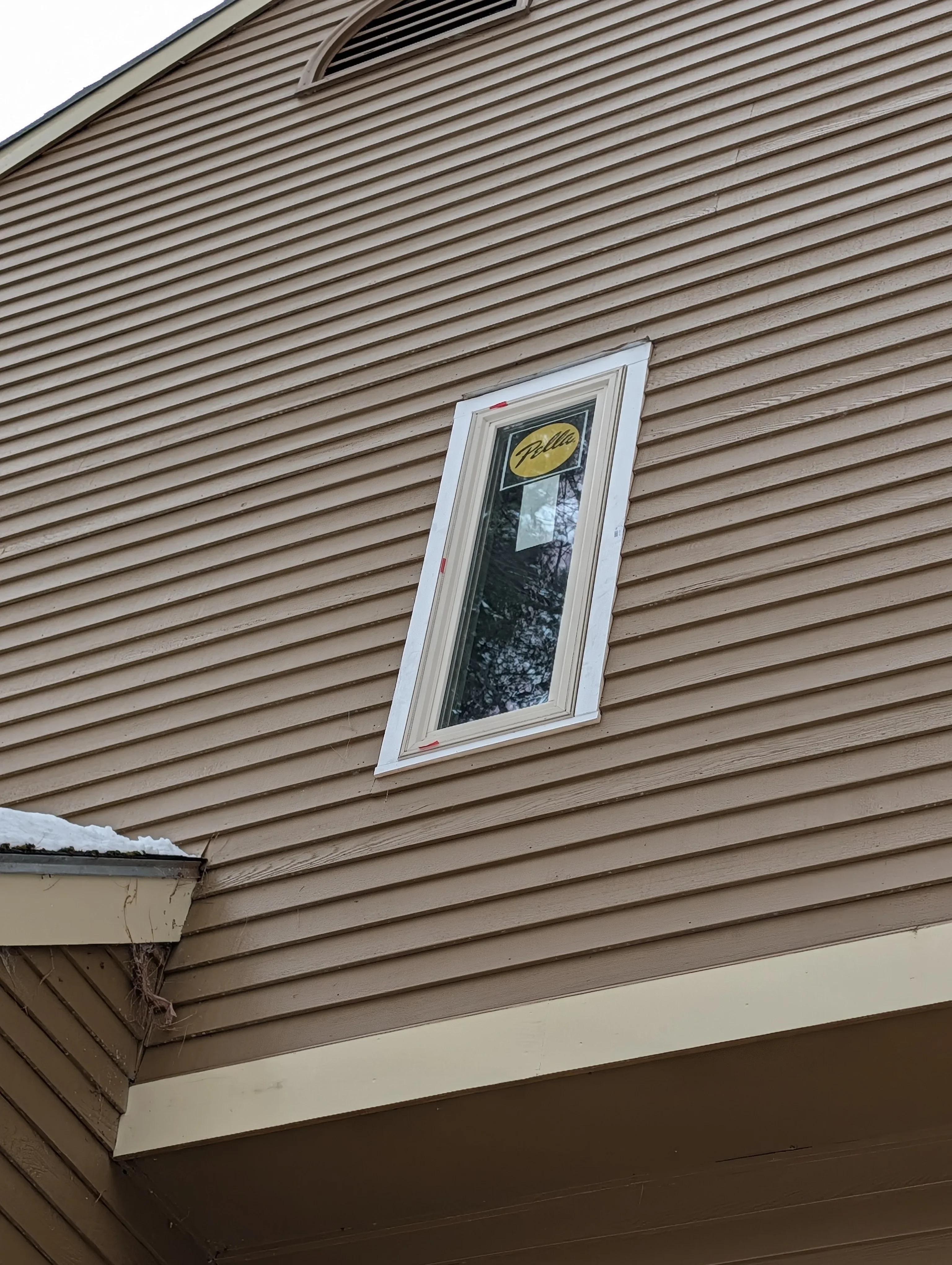 White vinyl window installed in horizontal siding with white trim and proper flashing