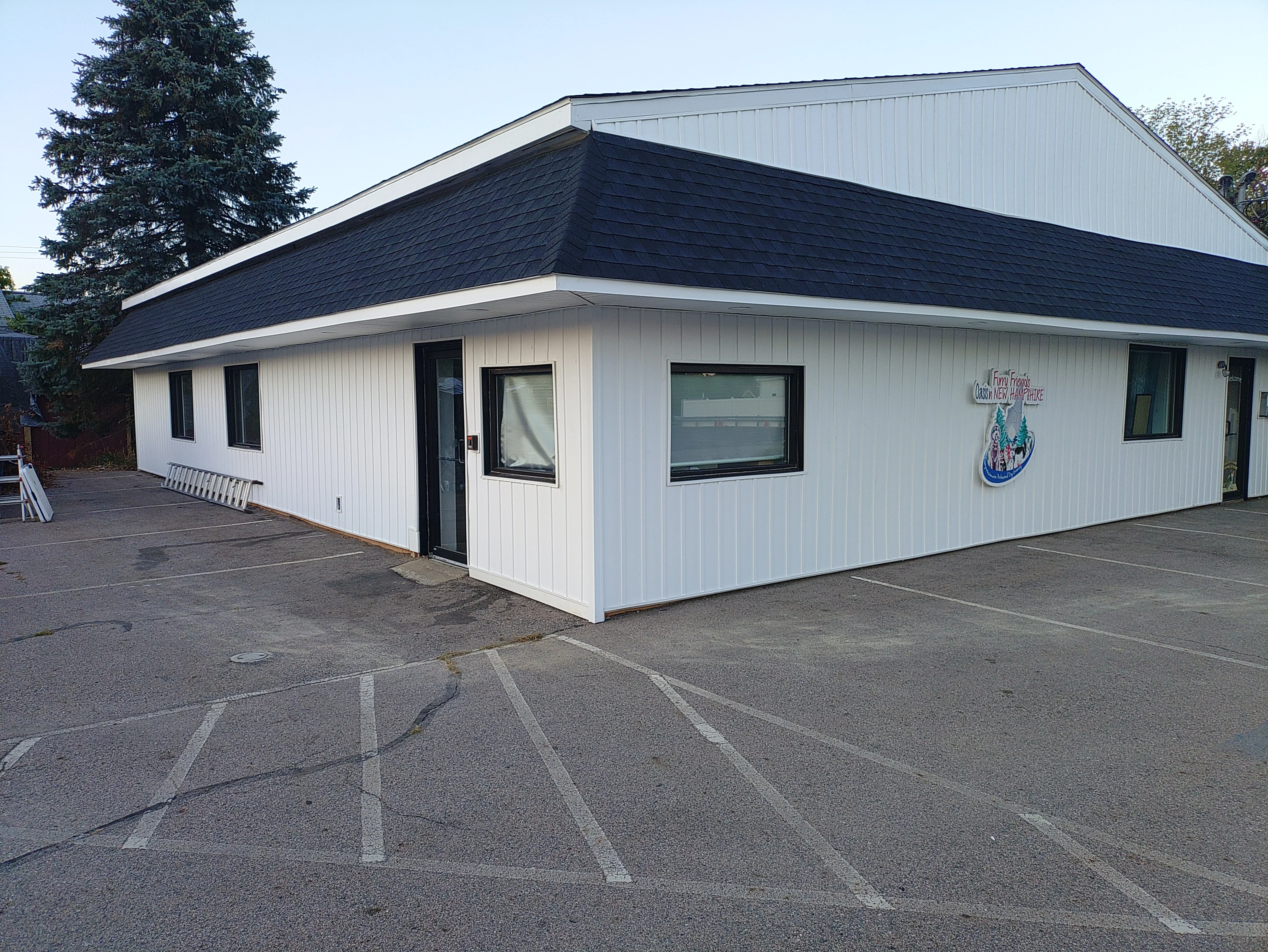 Modern commercial building with black shingle roof and white metal siding