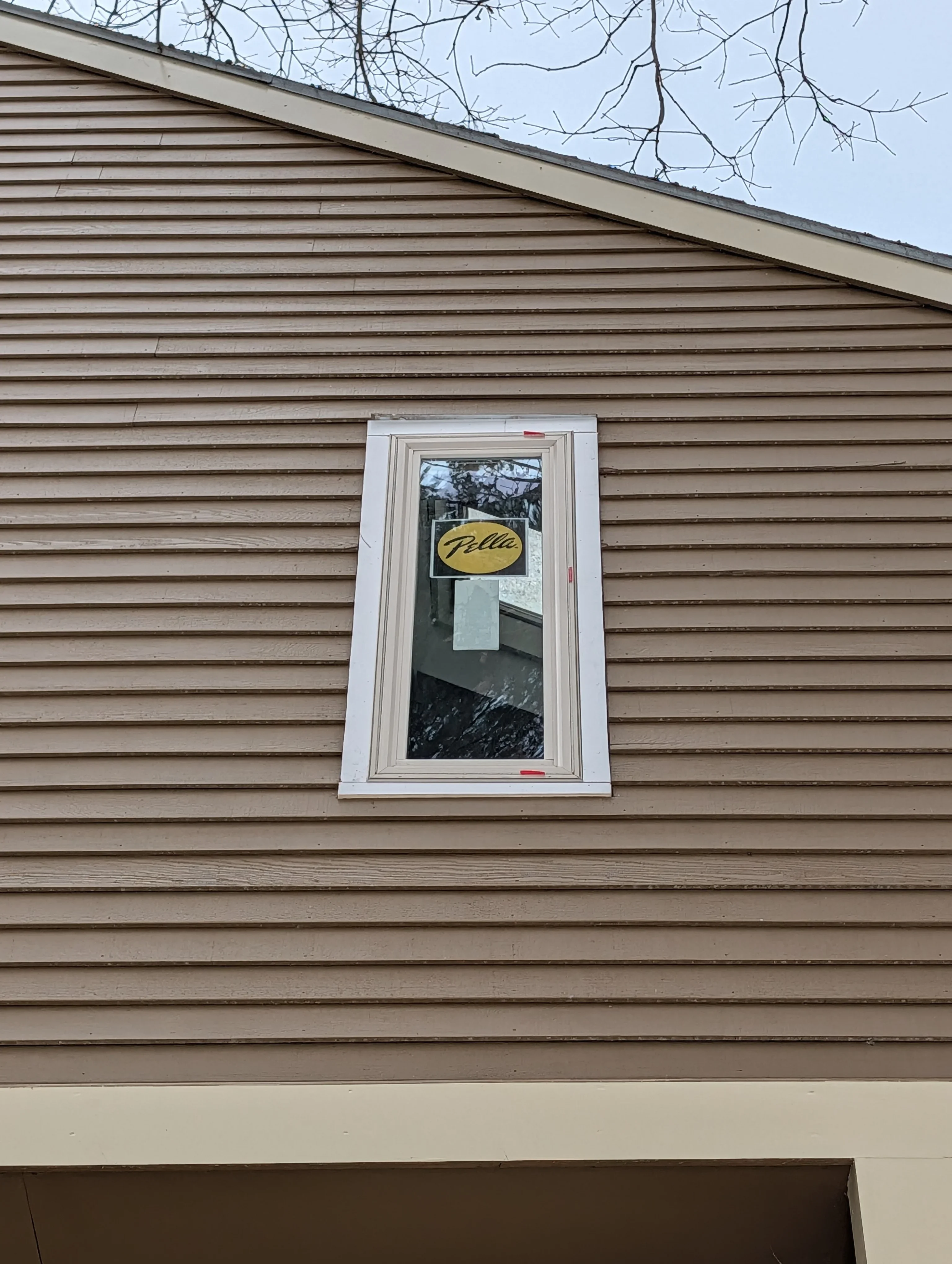 White vinyl window with trim installed on tan horizontal siding