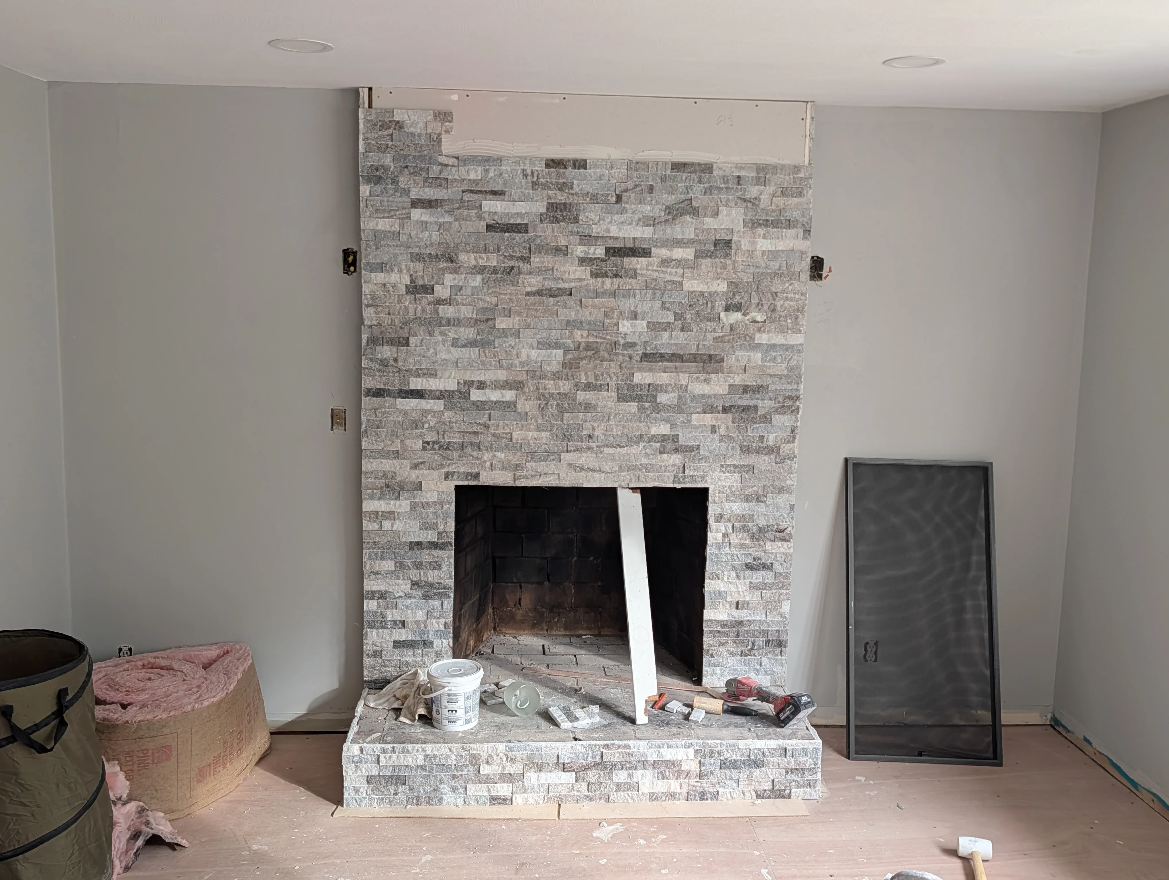 Gray and white stacked stone fireplace surround with hearth and black firebox opening