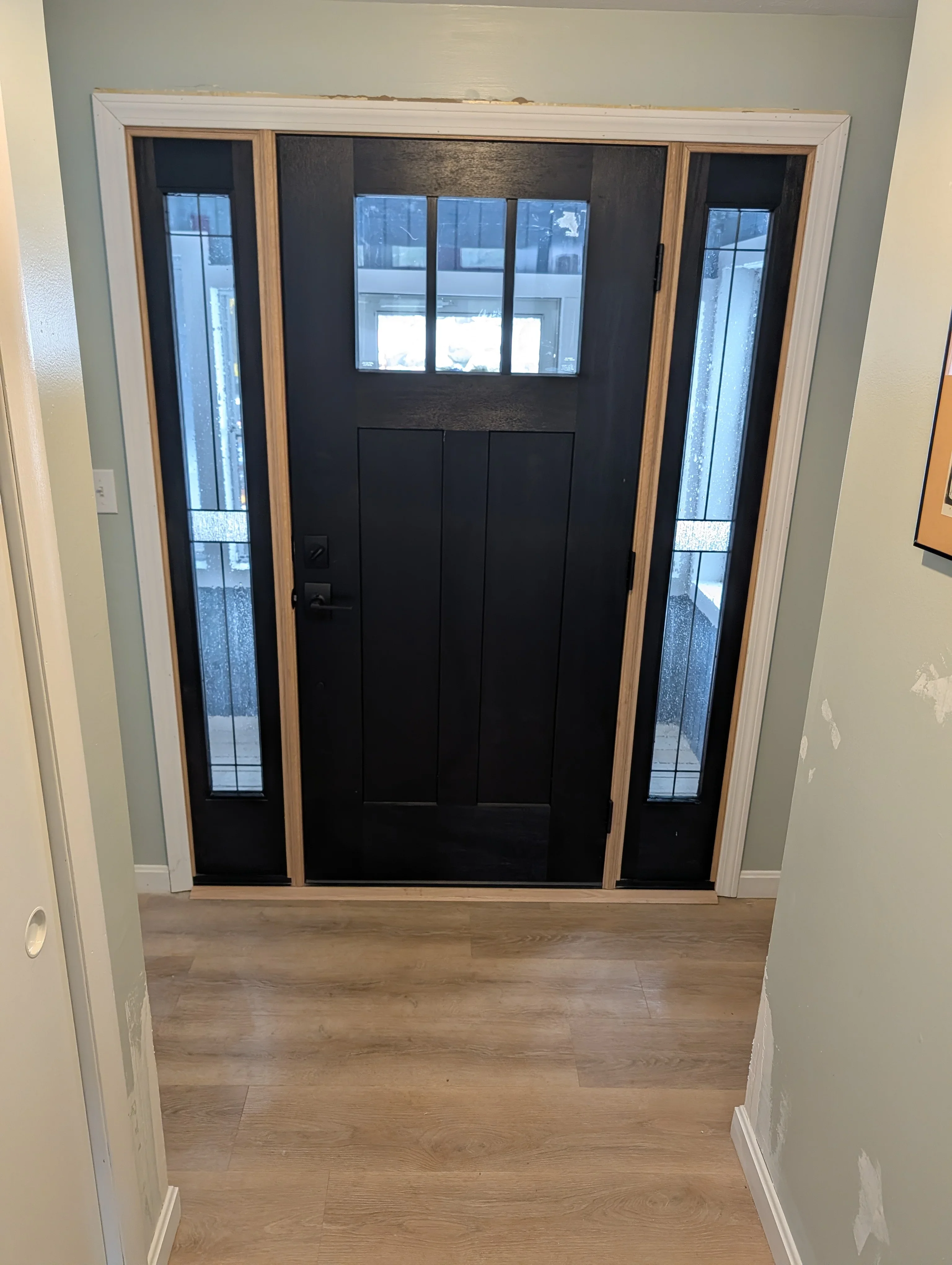 Black entry door with transom window and sidelights in white trim frame