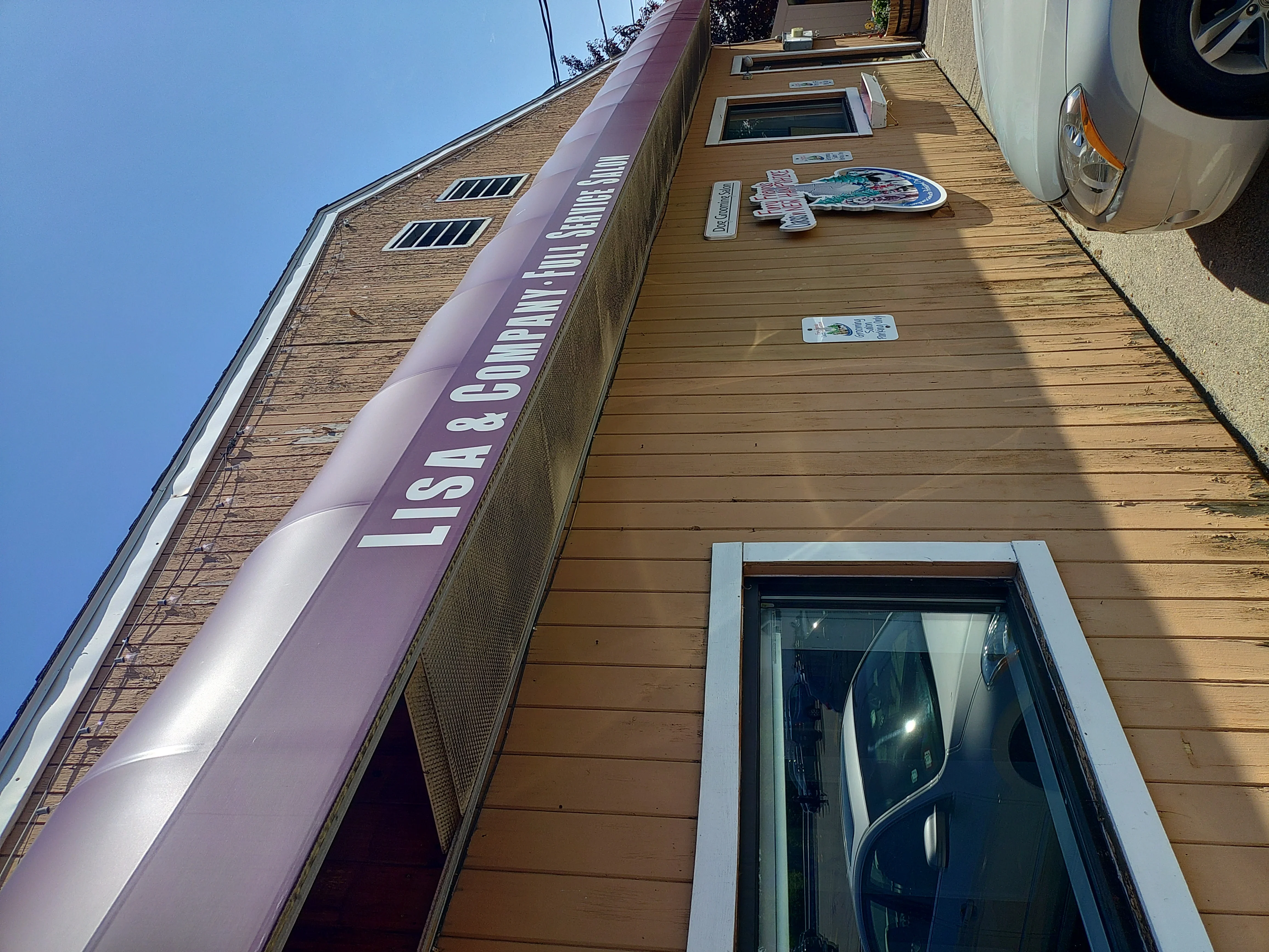 Newly installed tan composite siding on residential home with window trim and signage
