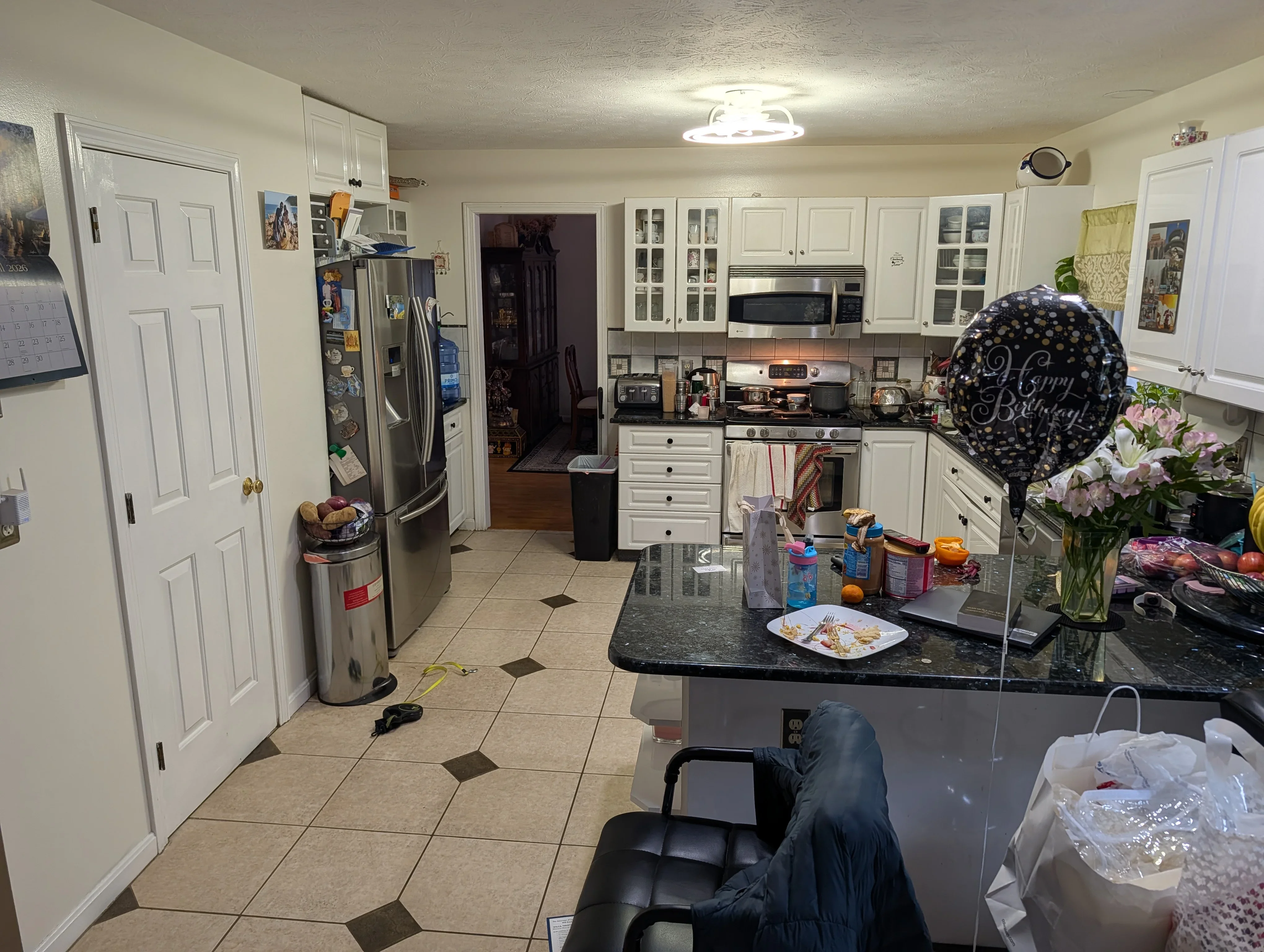 Modern kitchen with white cabinets, black granite counters, and stainless steel appliances