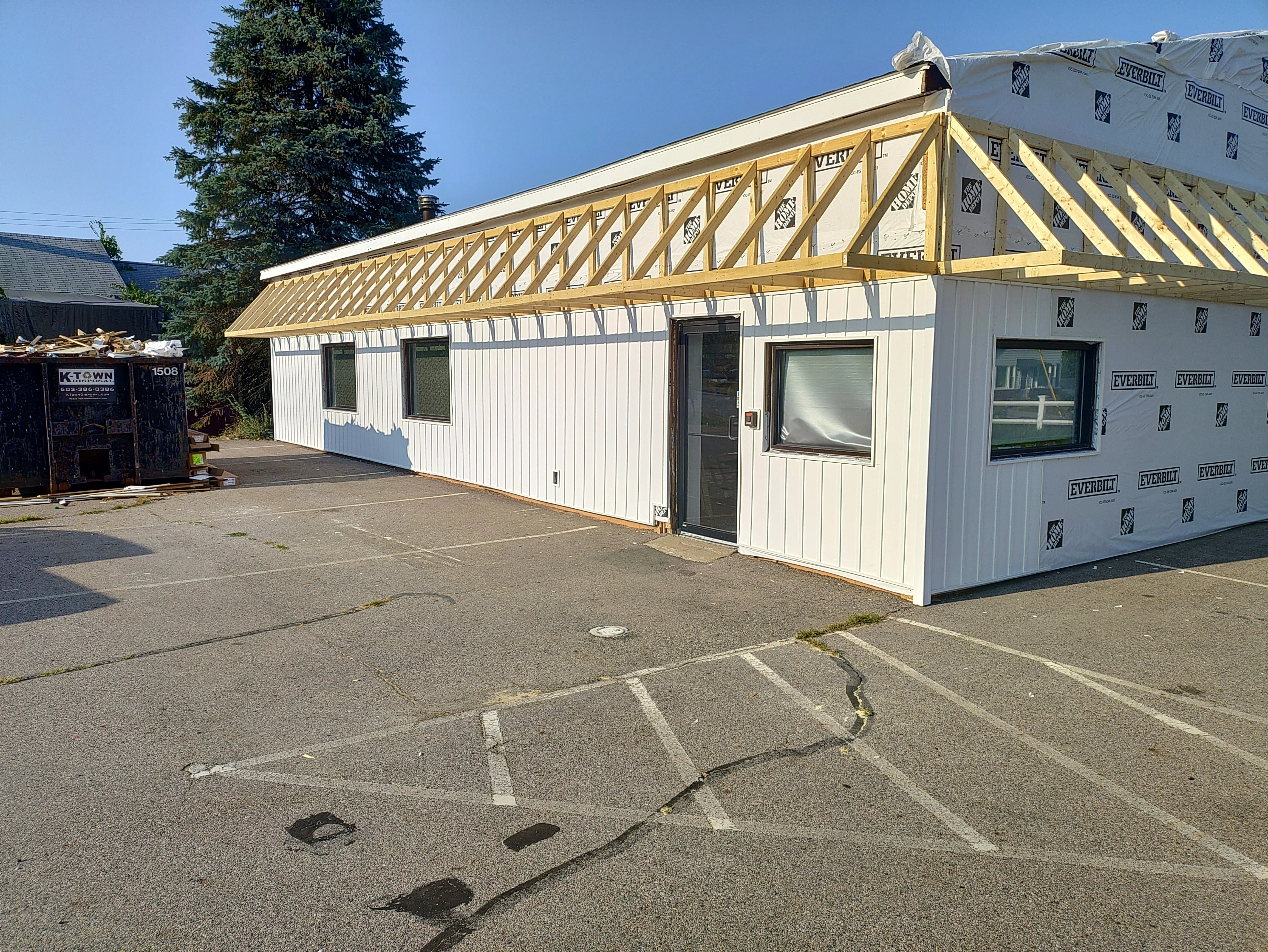 New pitched roof with yellow framing and white metal siding on residential structure