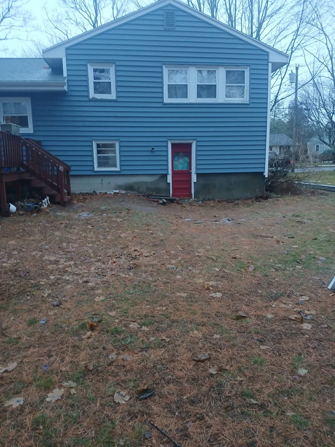 Blue vinyl sided two-story house with white trim and red entry door