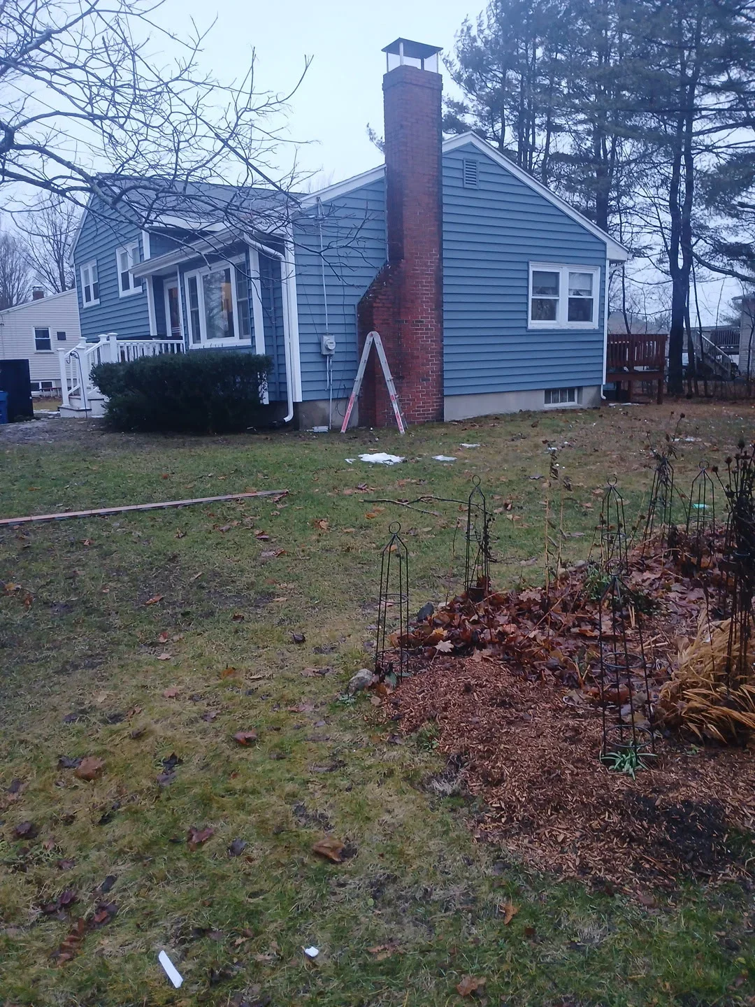Blue vinyl sided home with red brick chimney and white trim in Greenville, NH