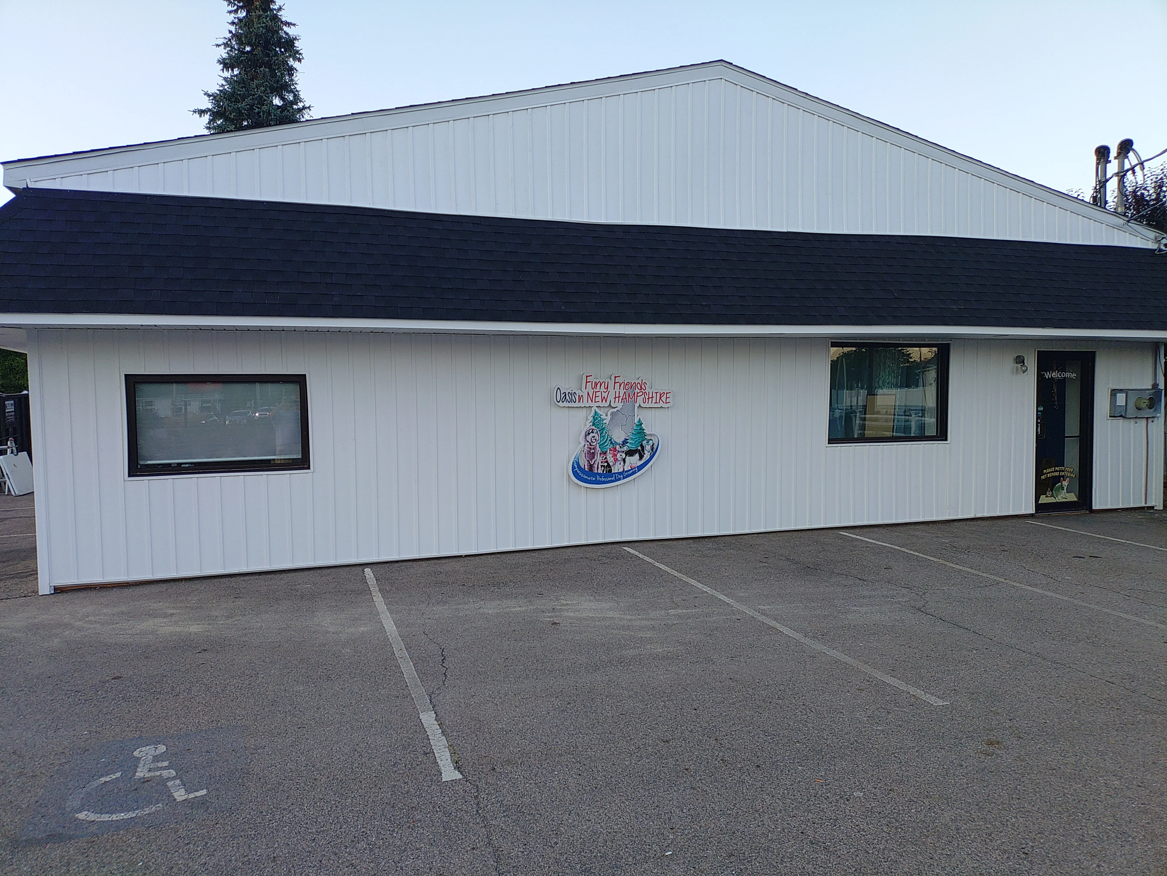 Commercial building with dark shingle roof and white metal siding exterior