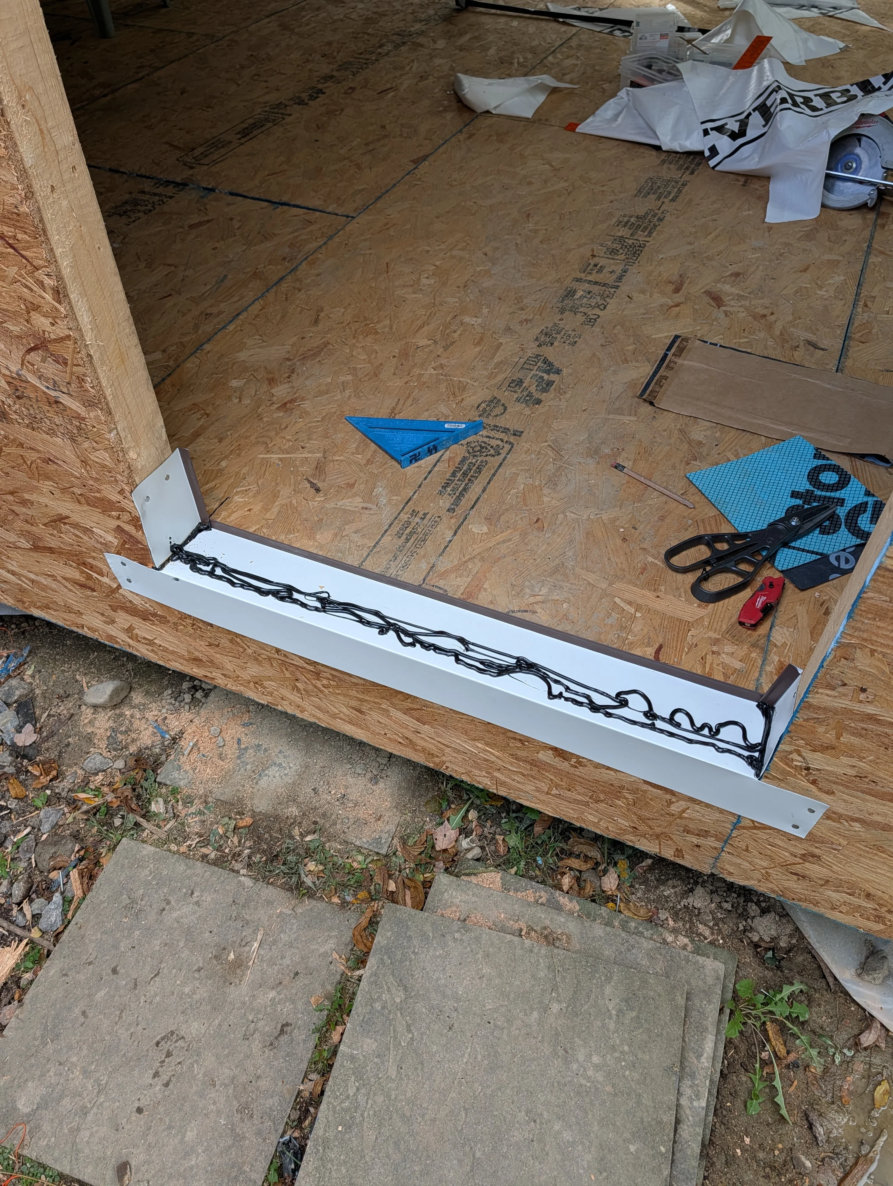 White aluminum soffit and fascia trim installation with black gutter chain during roofing project