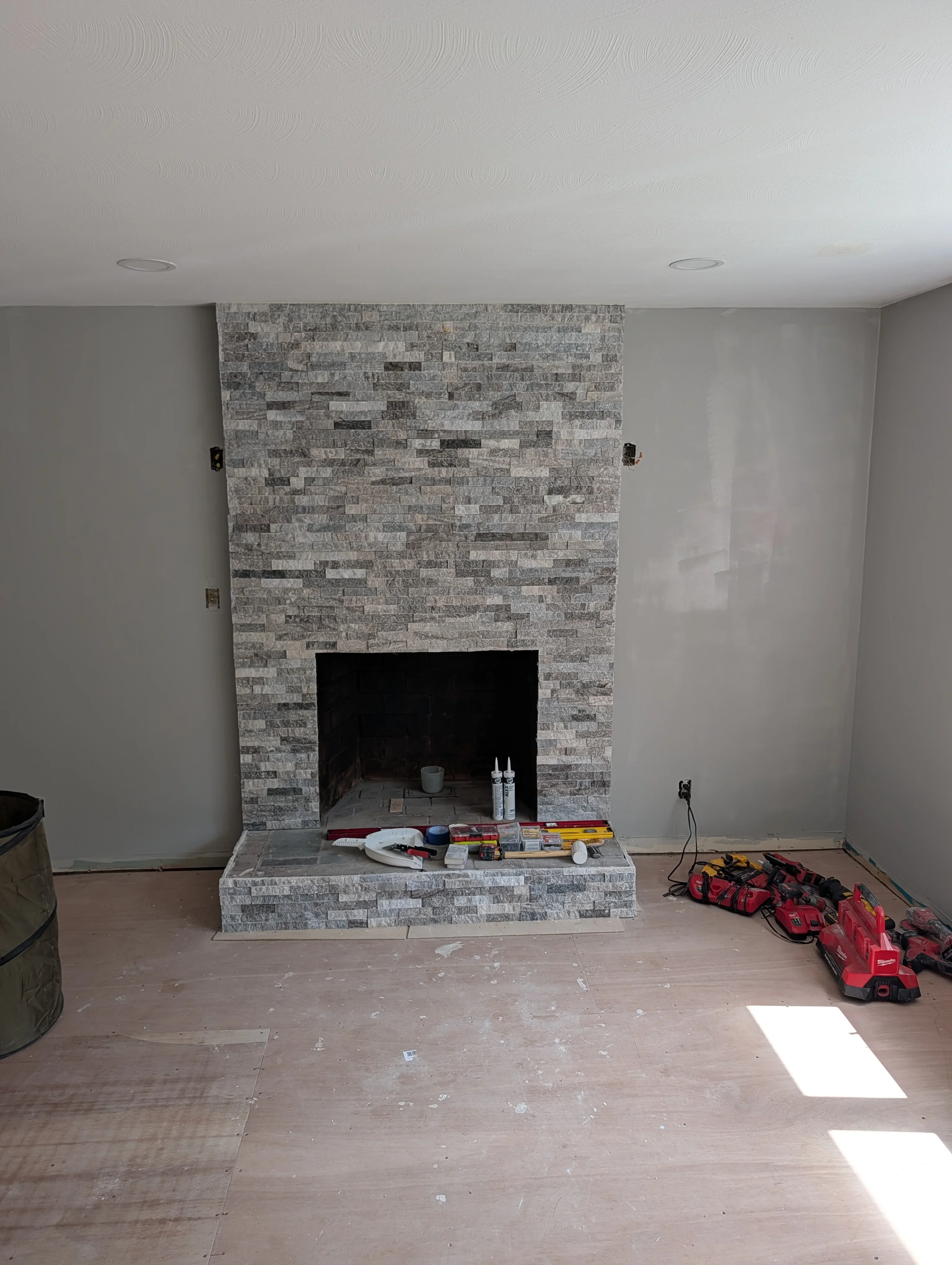 Gray stacked stone fireplace surround with black opening and finished hearth base