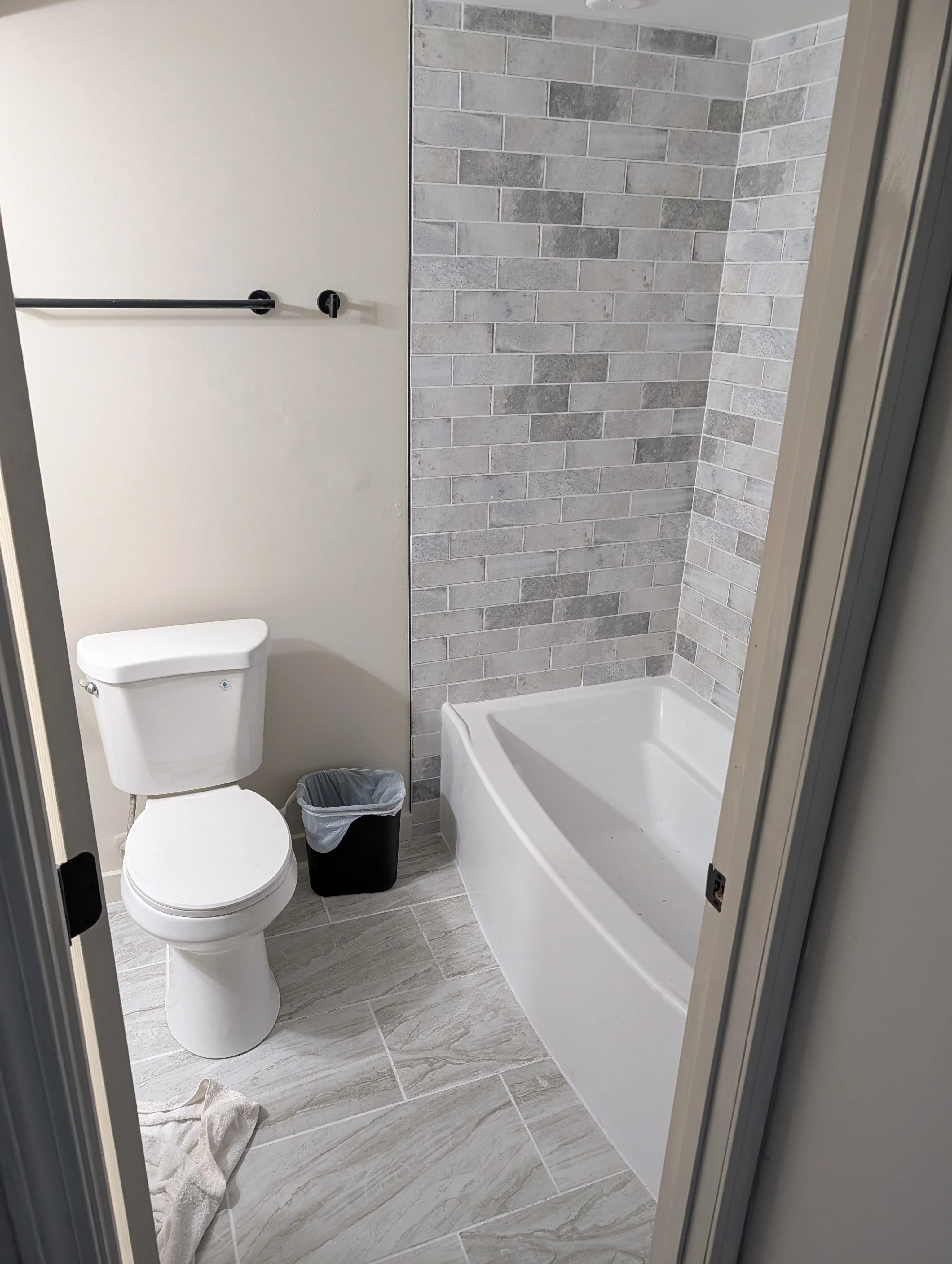 Modern bathroom with gray subway tile shower, white fixtures, and wood-look floor tile