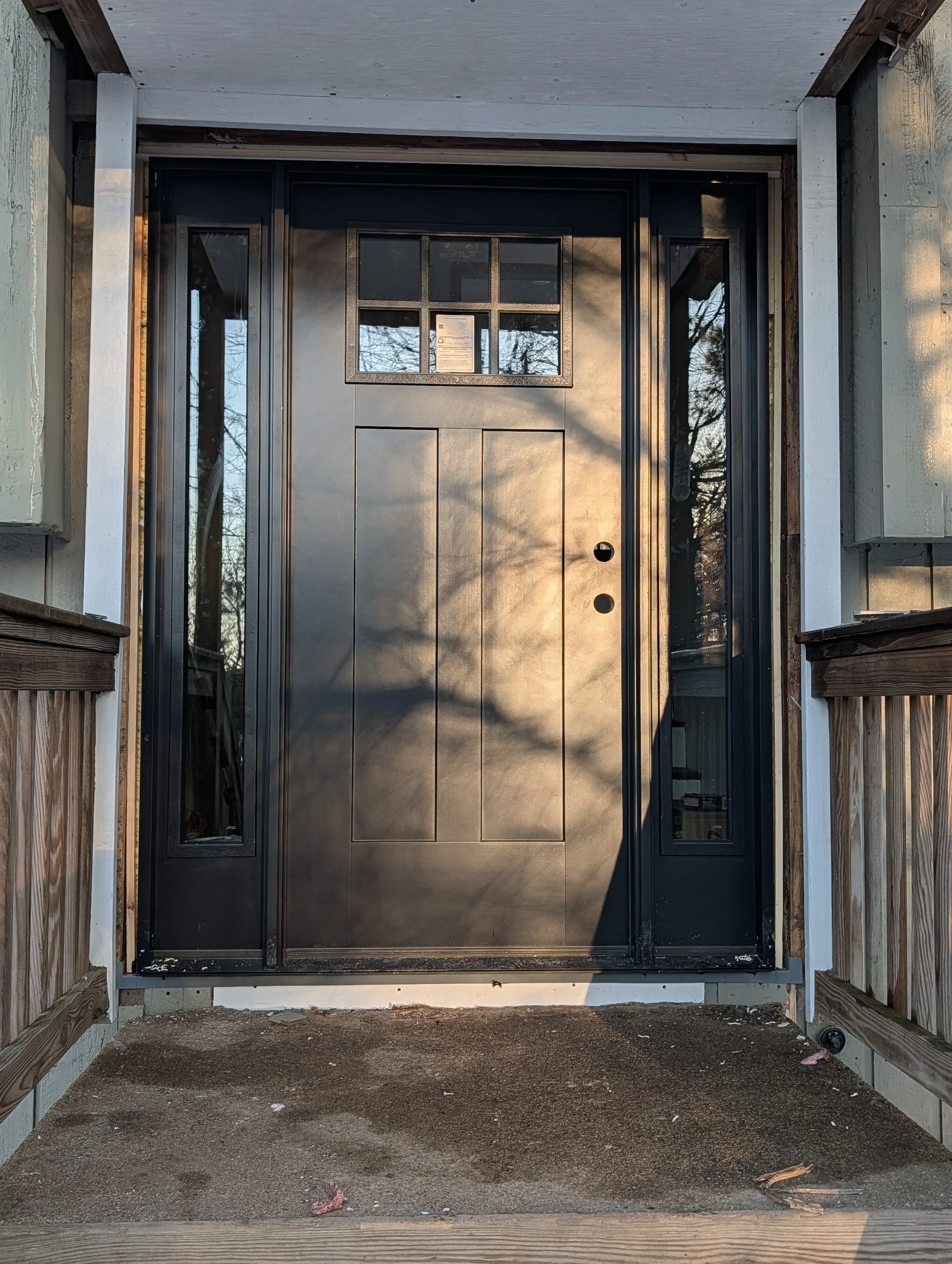 Black steel entry door with transom window and sidelights on residential home