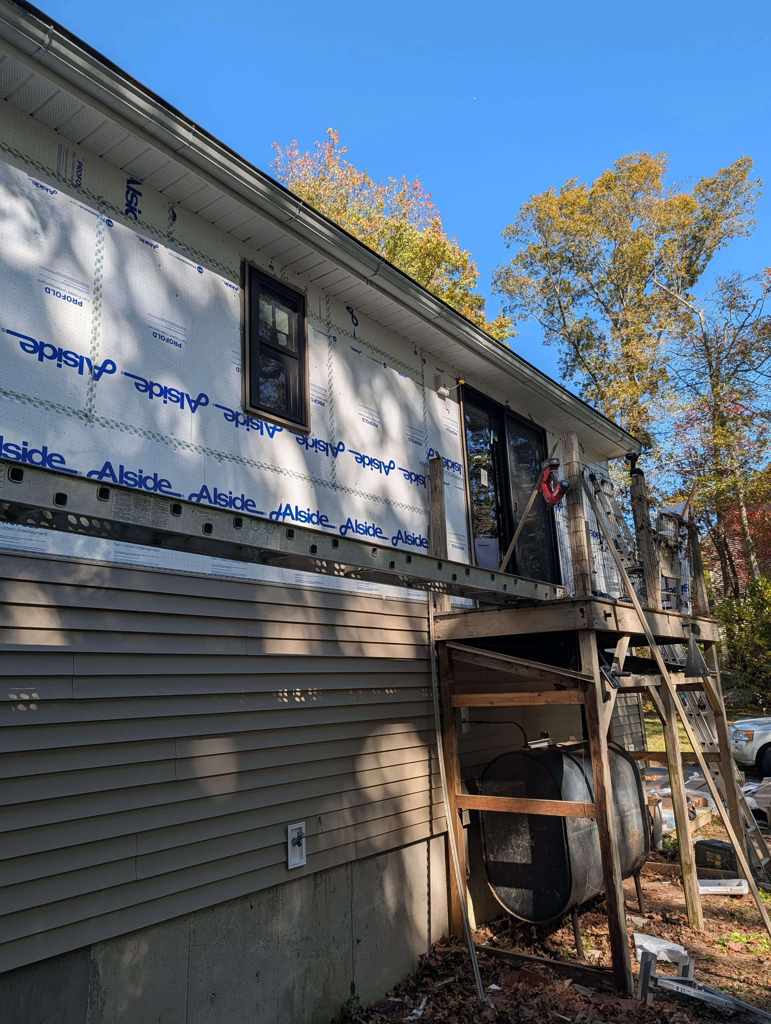 Mobile home siding installation with new lap siding and Alside wrap under autumn trees